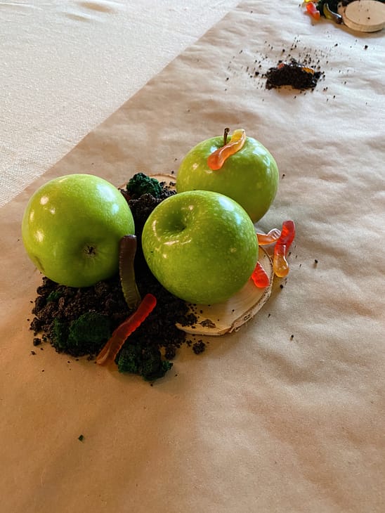 up close critter table decorations with apples, gummy worms, crushed Oreos, and edible moss