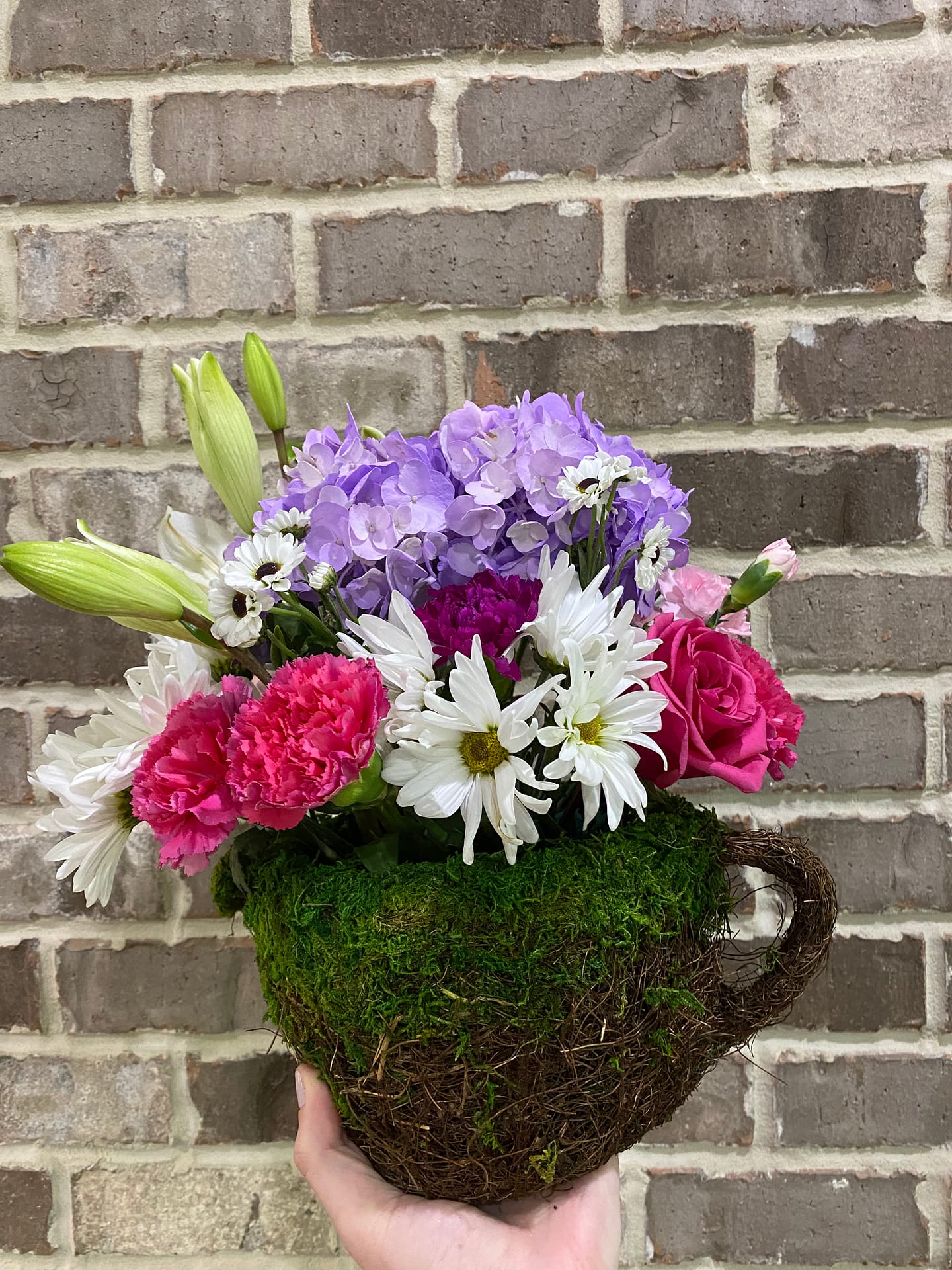 Grocery store flower arrangement in watering pot vessel.